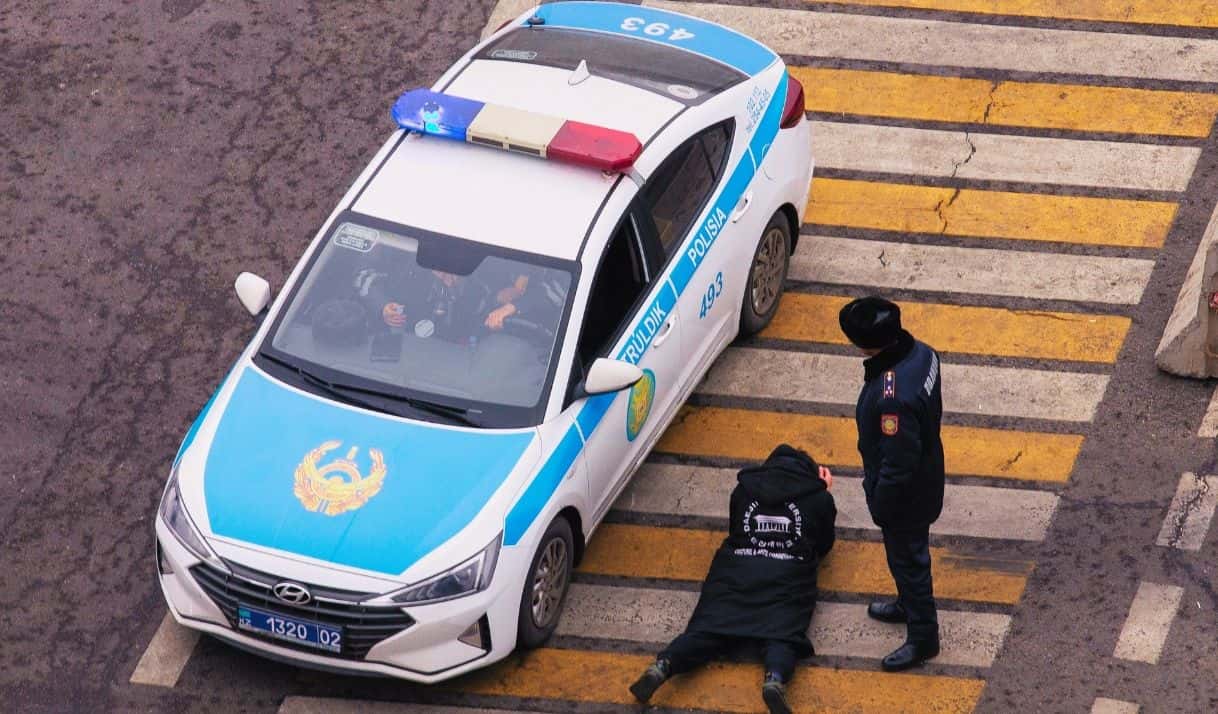 Un policía vigila a un hombre mientras otros agentes comprueban su documentación en un cruce en Almaty, Kazajistán, el lunes 10 de enero de 2022. (AP Foto/Vasily Krestyaninov)